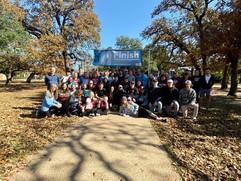 Large group photo of all participants gathered under the finish line/banner