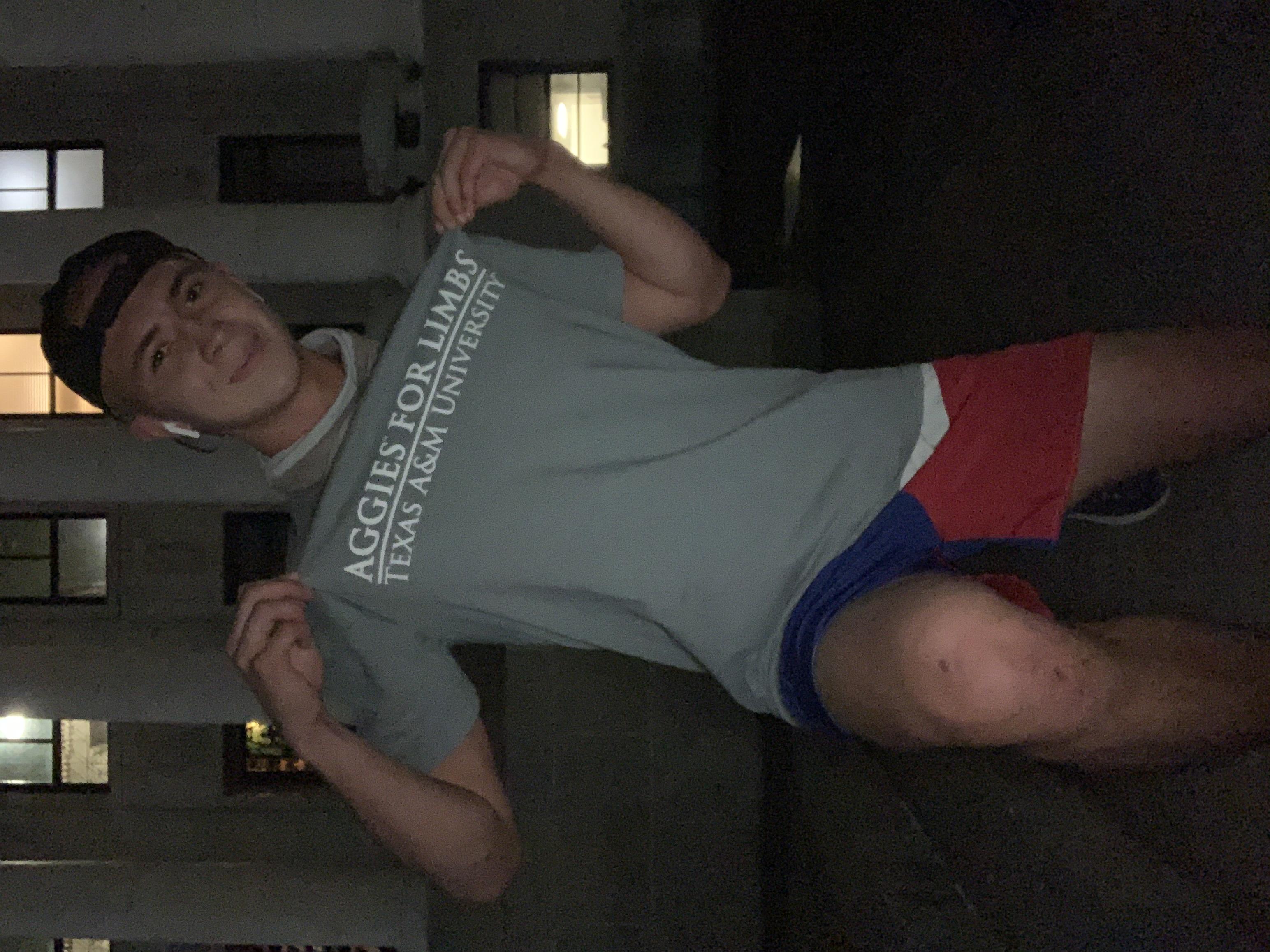AFL member showing organization t-shirt during nighttime walkathon segment with campus architecture in background