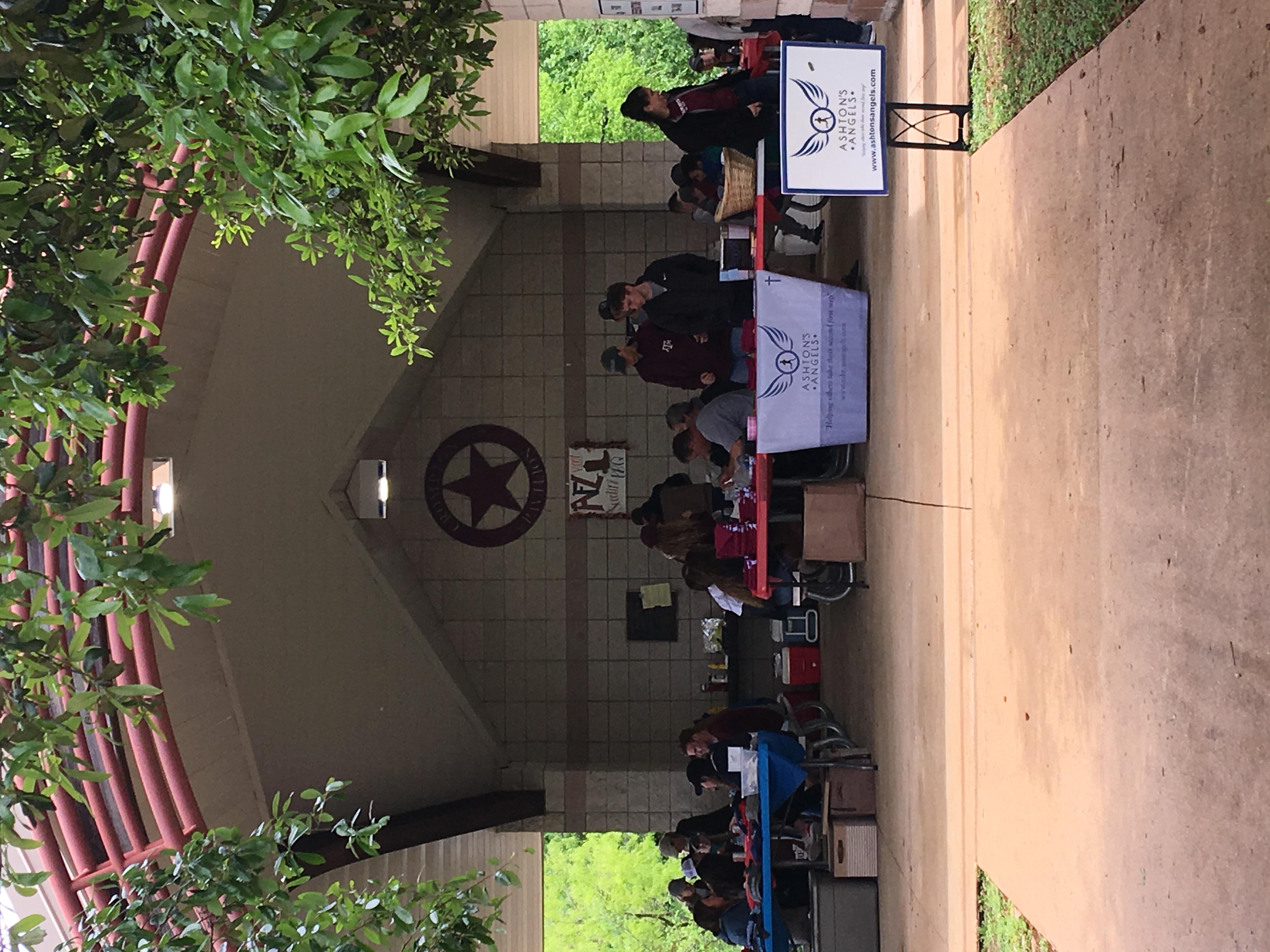 Event registration setup with Aggies for Limbs banners and check-in tables at a covered pavilion with a Texas star emblem